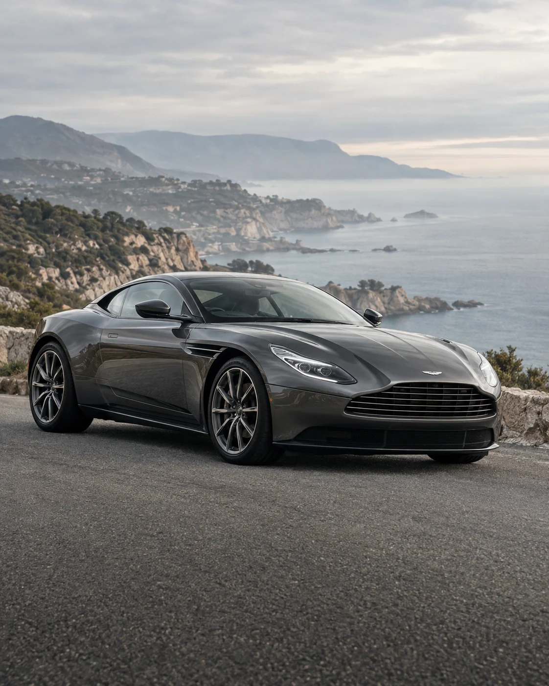 A graphite Aston Martin on a coastal road above the sea